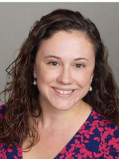 Tessa Ditonto in a pink and blue printed blouse in front of a gray background