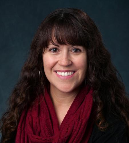 Celeste Montoya with a red scarf in front of a dark background