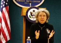 Ethel speaking at microphone in front of Foreign Press Center sign and American flag