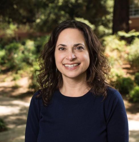 Jennifer Merolla in a navy blue shirt in front of a blurry background of greenery